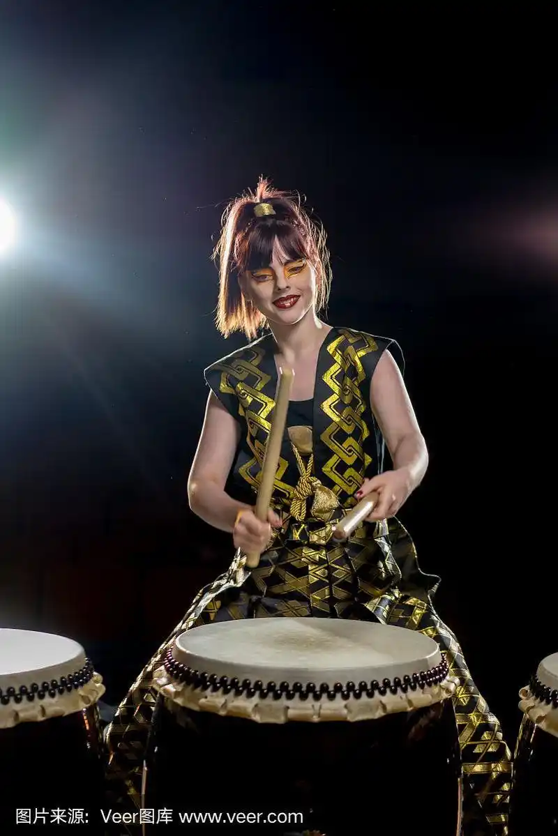 美丽的亚洲鼓手女孩与鼓槌,工作室拍摄在一个黑暗的背景.