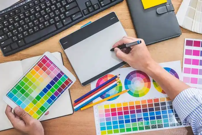 男性创意平面设计师的形象致力于颜色选择和绘制图形平板在工作场所与