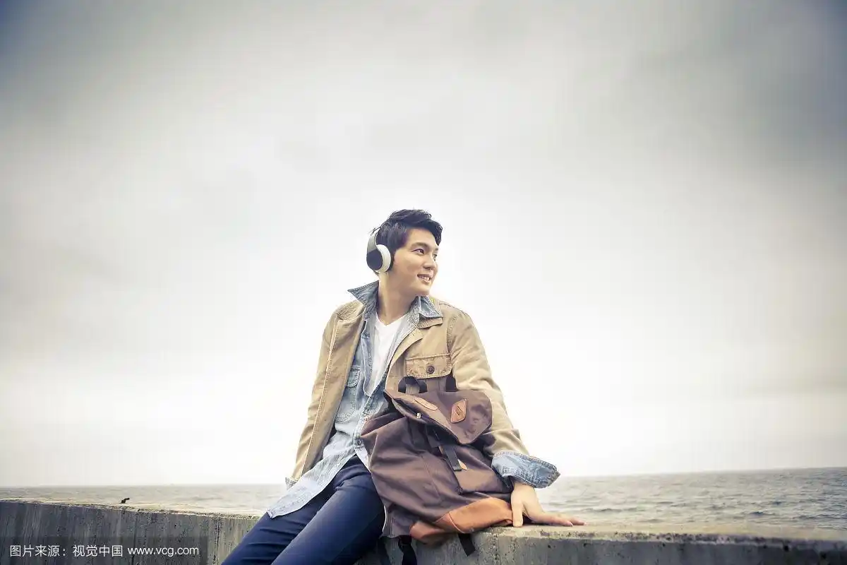 一个人坐在海边用耳机听音乐的照片