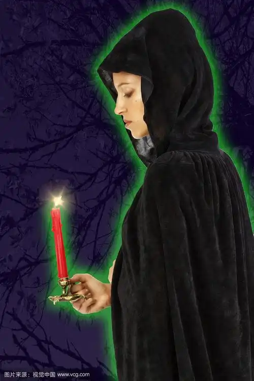 侧面寡妇女巫在黑色头巾与点燃的蜡烛绿色辉光