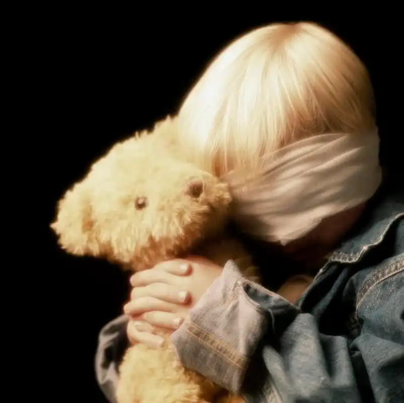 用绷带包扎眼睛和控股泰迪熊的男孩