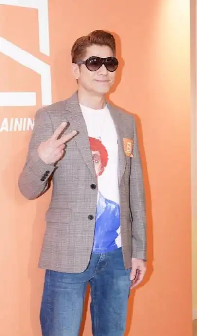 郭富城里面穿白色潮流t恤,外面搭配灰色西装,下身穿蓝色牛仔裤,脚踩