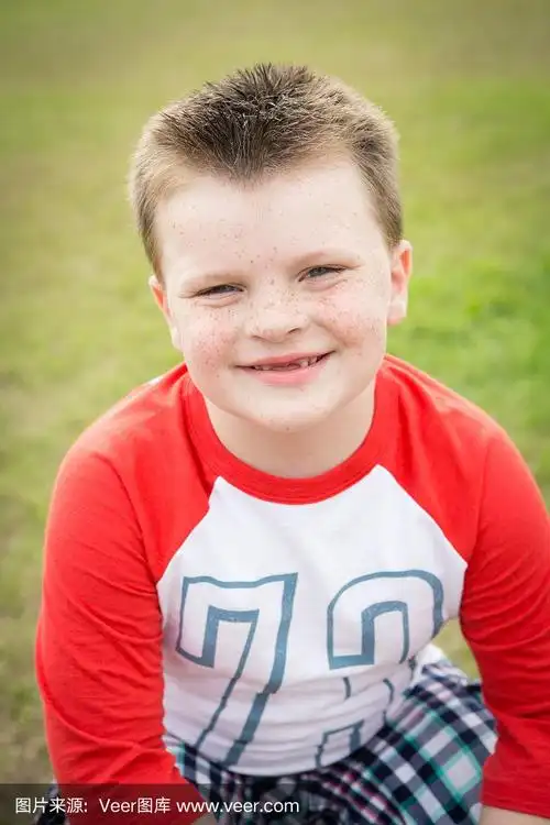 满脸雀斑的快乐小男孩坐在外面