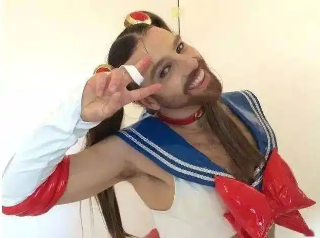 照片的他,穿着女装,化着彩色的眼影和口红,还戴着各式各样的假发,脸上