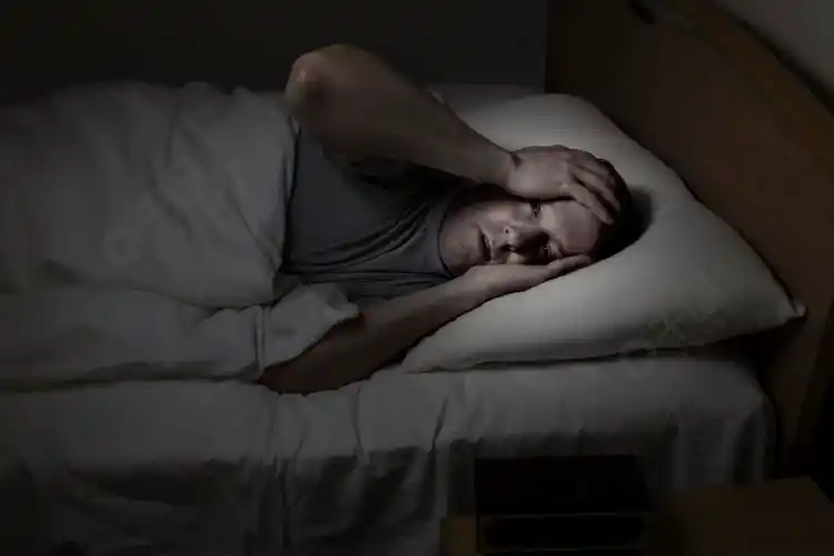 成熟的男人睁大眼睛双手放在额头上晚上因失眠而无法入睡