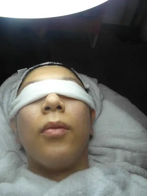 美容师打开灯,开始要清洁粉刺了,将眼部盖上纱布.