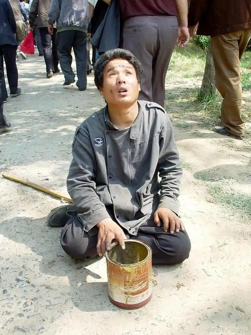 一个盲人乞丐戴着墨镜在街上行乞.