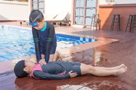 男孩帮助溺水的儿童女孩在游泳池通过做 cpr照片
