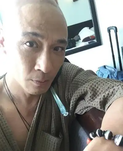 "照片中,吴镇宇身穿橘黄色袈裟,光头造型十分惹眼.