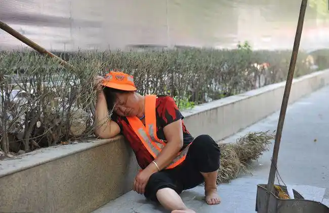 疲惫的环卫工席地而坐,在街头休息.每天工作10小时以上,真的累了!