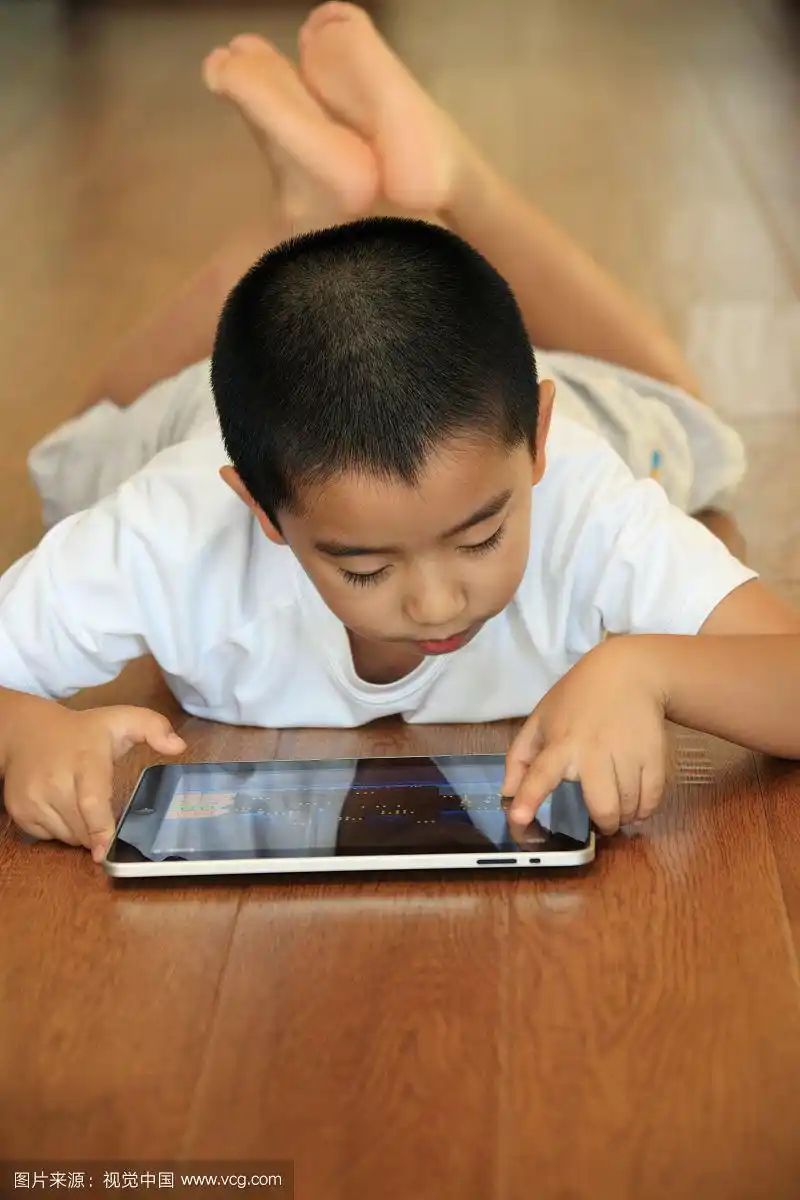 东方男孩趴在地板玩电脑