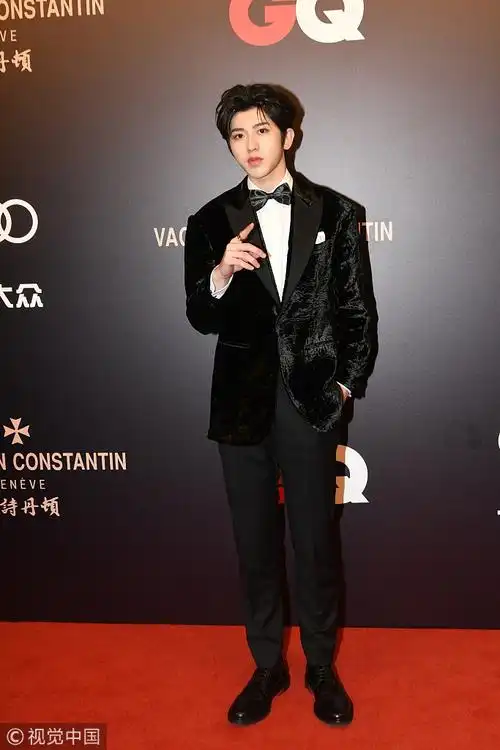 蔡徐坤身穿黑色丝绒西服套装,内搭白衬衣,打黑色领结,脚踩黑色系带