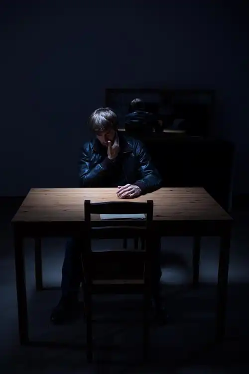 一个男子坐在黑暗的空房间里