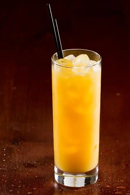 螺丝刀鸡尾酒,明亮的黄色发光的螺丝刀饮料送达一个黑暗的酒吧