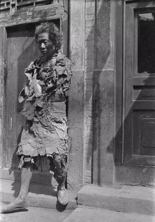 妇人用破烂不堪的衣服将孩子紧紧包裹在自己胸前,母子相依为