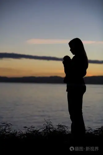 一名少女在日落祈祷在海边
