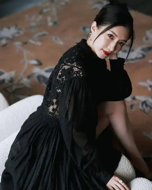 这是一张江疏影身穿黑色连衣裙,侧身坐在沙发上的照片.
