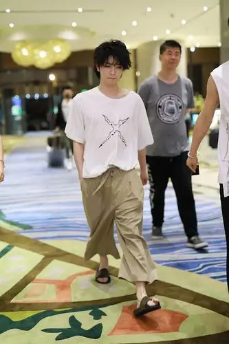 华晨宇单手插兜走路带风,脚上踩着一双黑色的凉拖,加上凌乱的发型