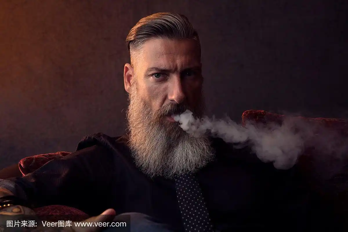 一个酷酷的留着胡子的吸烟男子的特写