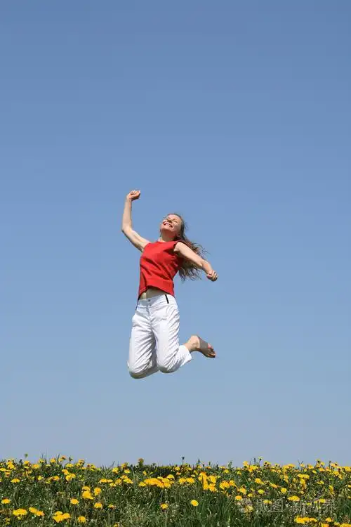 微笑快乐女孩跳在开花字段中