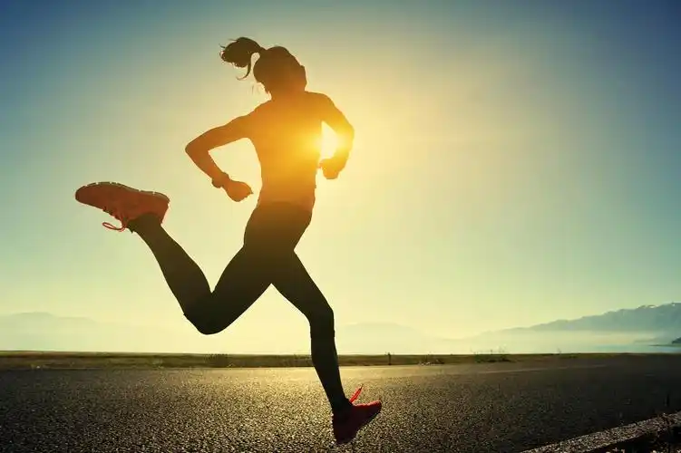 一名年轻女人在日出海边的道路上跑步运动健身户外跑步