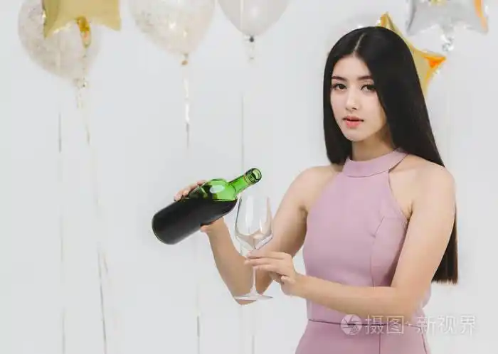 美丽的年轻亚洲女人粉红色倒酒在有趣的聚会白色背景与节日五颜六色的