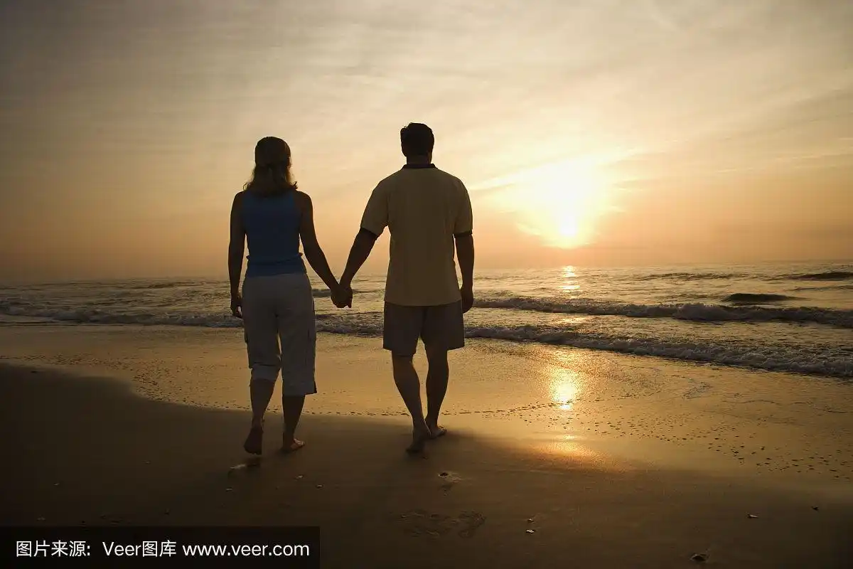 日落时分,一对情侣在海滩上牵着手