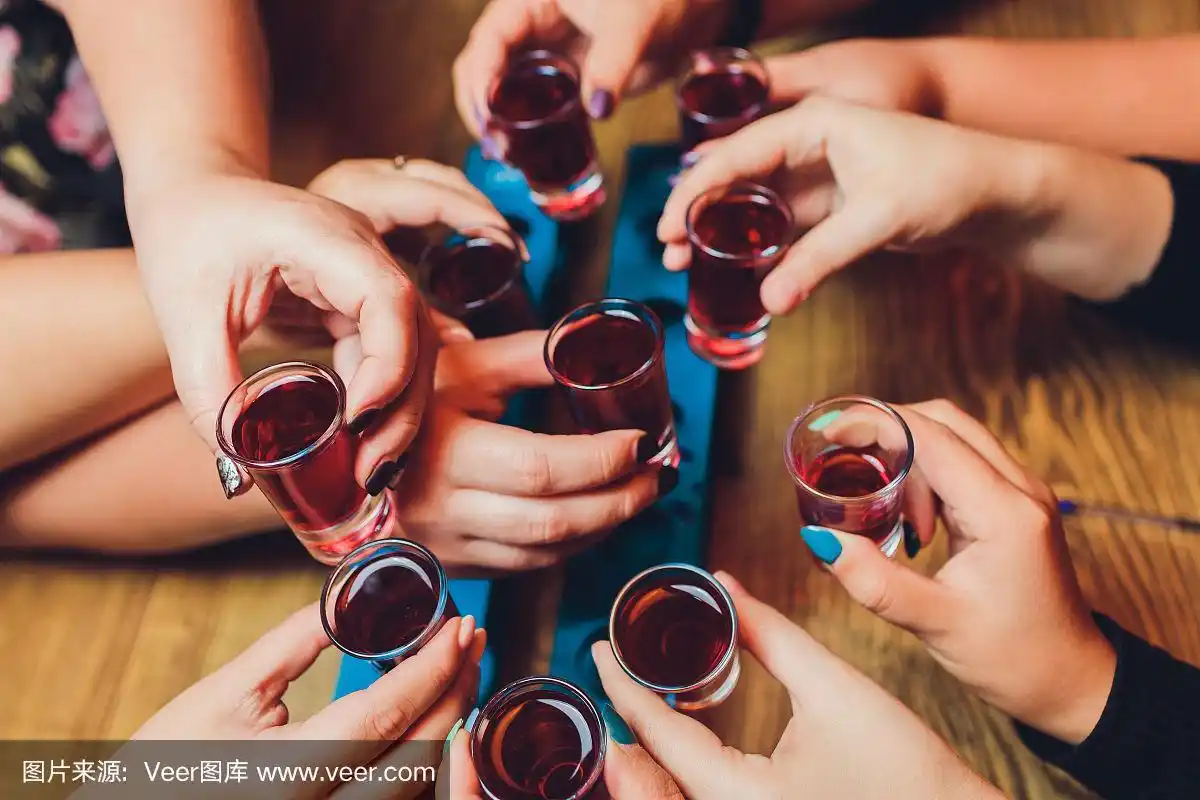 近距离拍摄的一群人与葡萄酒或香槟碰杯前的散景背景.