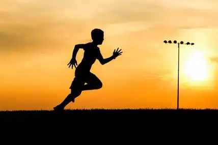 奔跑田一个运动男孩在北爱达荷州的日落田野上奔跑.照片