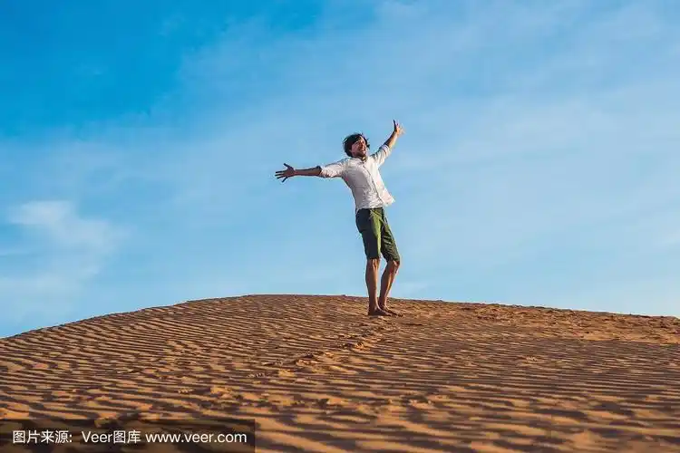 美丽的年轻人赤脚在沙漠的沙子上跳跃,享受自然和阳光.