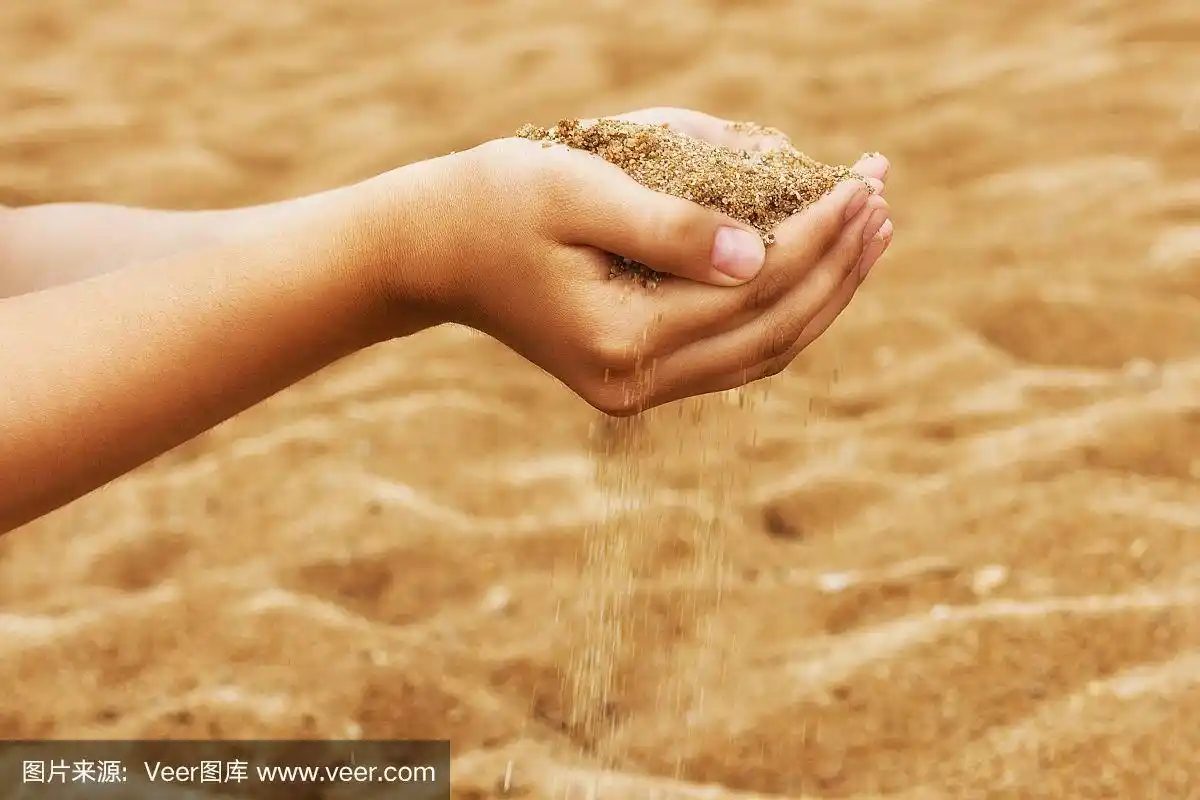 在张开的手掌里,沙子从指间倾泻而下.手里拿着沙子的年轻女人