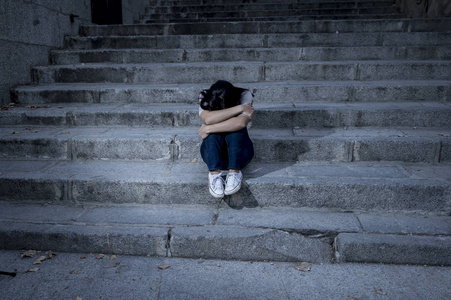 孤独忧伤美丽而忧伤的拉美裔女人,绝望和沮丧的坐在城市街道楼梯上