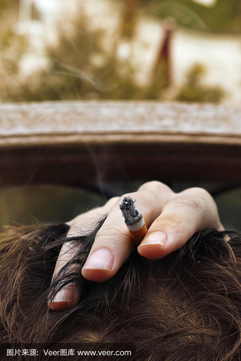 男人的手放在头上,手指间夹着香烟