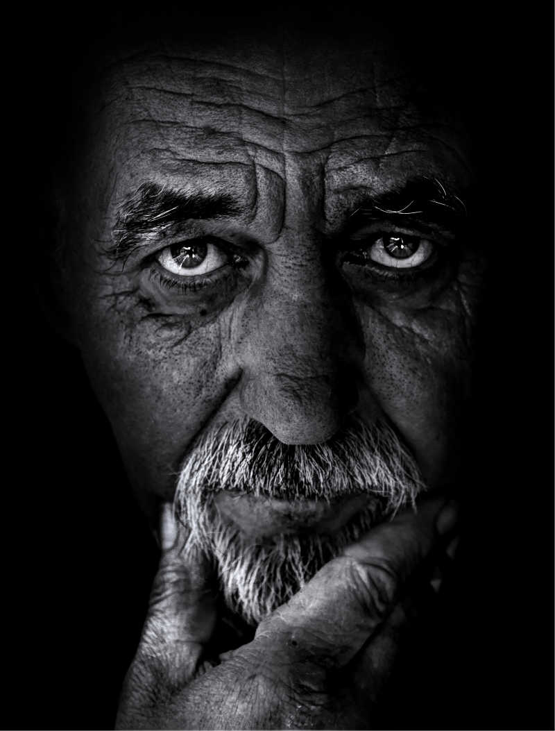 黑色背景下伤感严肃的老人的黑白图像