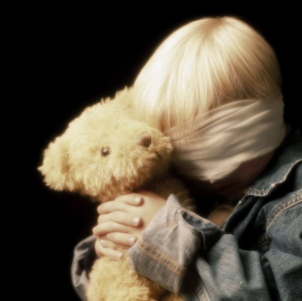 用绷带包扎眼睛和控股泰迪熊的男孩