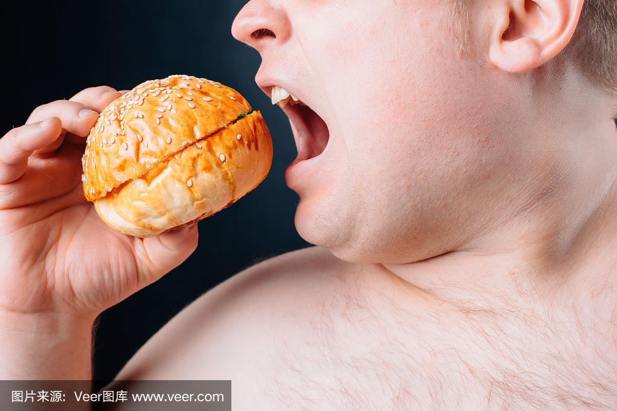 黑色背景下一个大肚子的胖子.饮食.