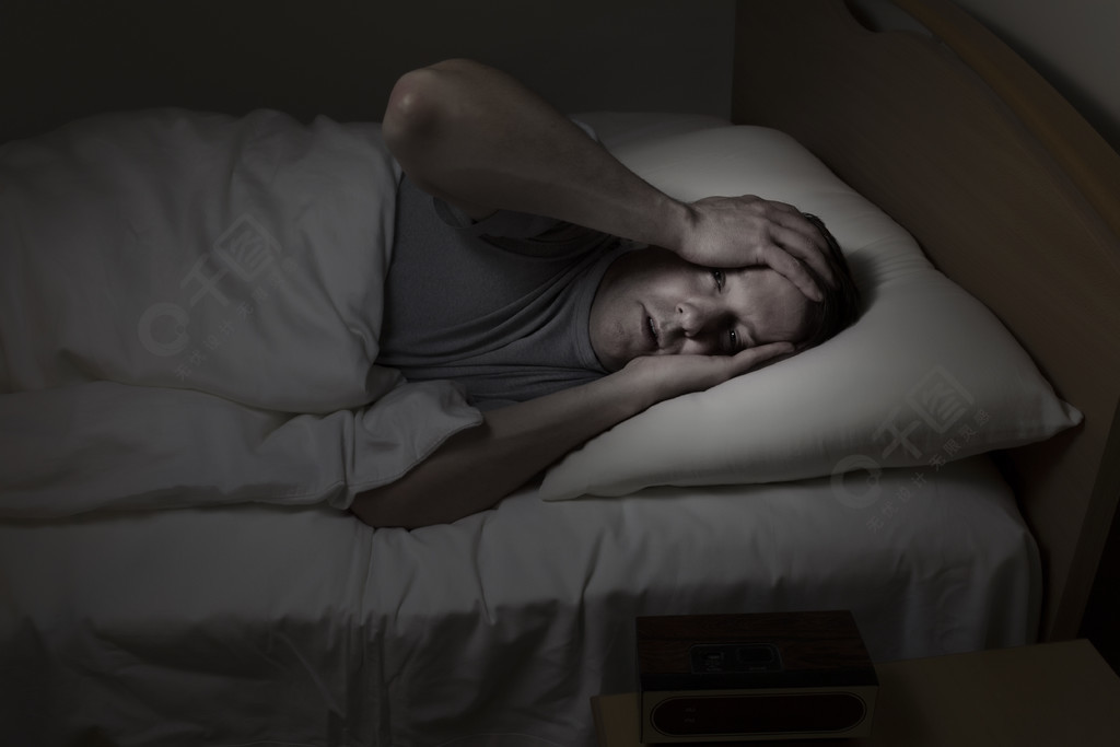 成熟的男人睁大眼睛双手放在额头上晚上因失眠而无法入睡