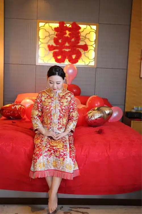 穿着盛装中式传统服饰的新娘,羞涩地坐在婚床边等待新郞的到来