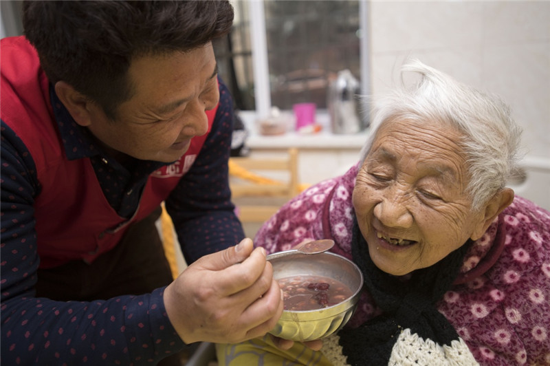 1月5日,武汉好人圈志愿服务协会的志愿者在喂老人吃腊八粥.