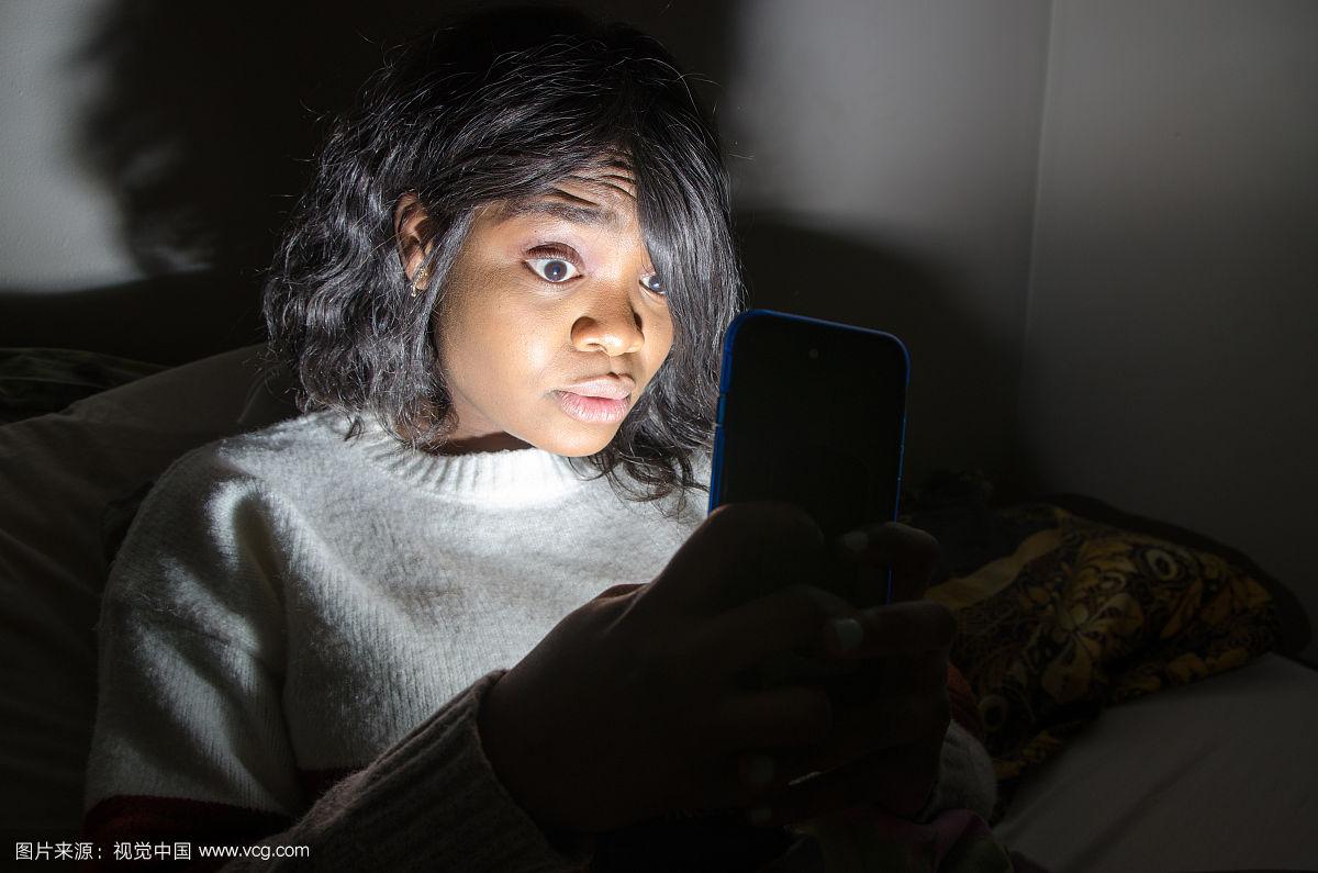 年轻黑人妇女在黑暗中使用手机