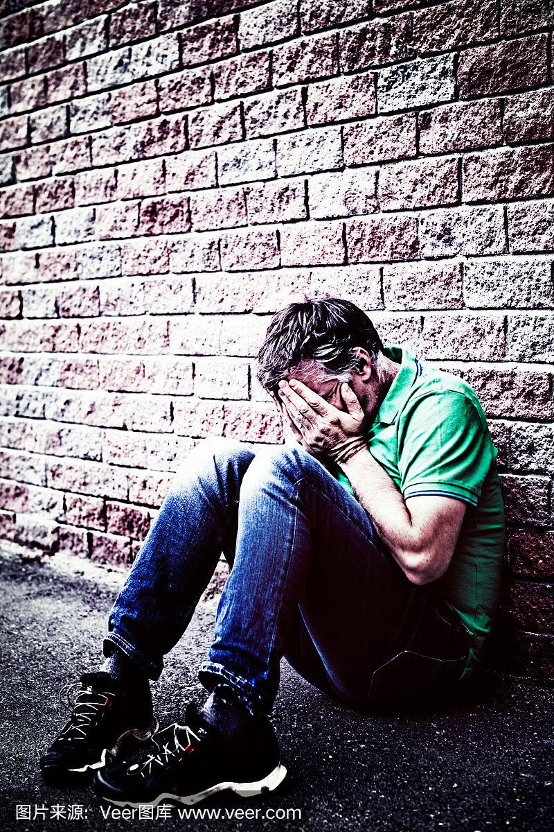 双手捂着脸,绝望的男人蹲着哭泣