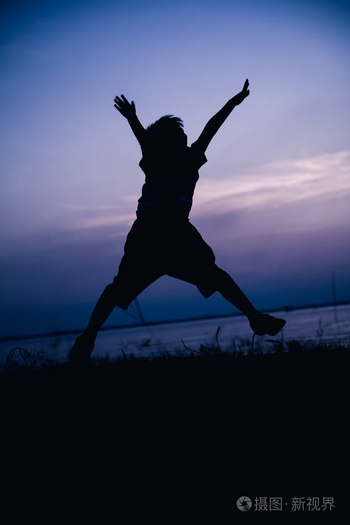 剪影的孩子享受和跳跃在滨江的背影