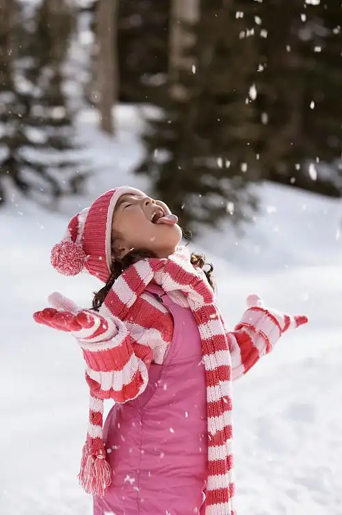 一个女孩伸出舌头去接雪花的侧影图片
