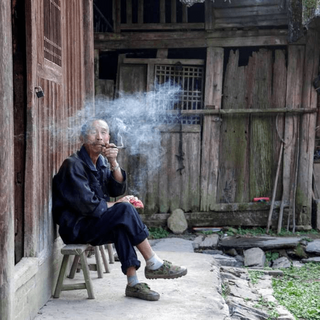 等老人休闲的时候总会拿张小凳子坐在门口抽上点烟