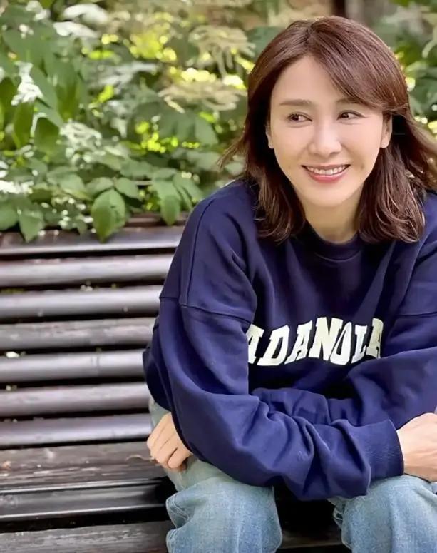 52岁黎姿骑车郊游,穿卫衣牛仔裤身材苗条,坐长椅晒太阳好惬意