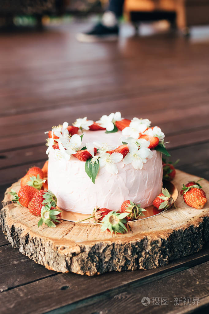 用草莓装饰的白色蛋糕放在木桌上的托盘上.复制文本.顶部视图.特写