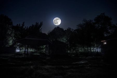 哥特式的窗口和月亮夜晚用月亮或老式乡村住宅在森林中建造的山夜景观