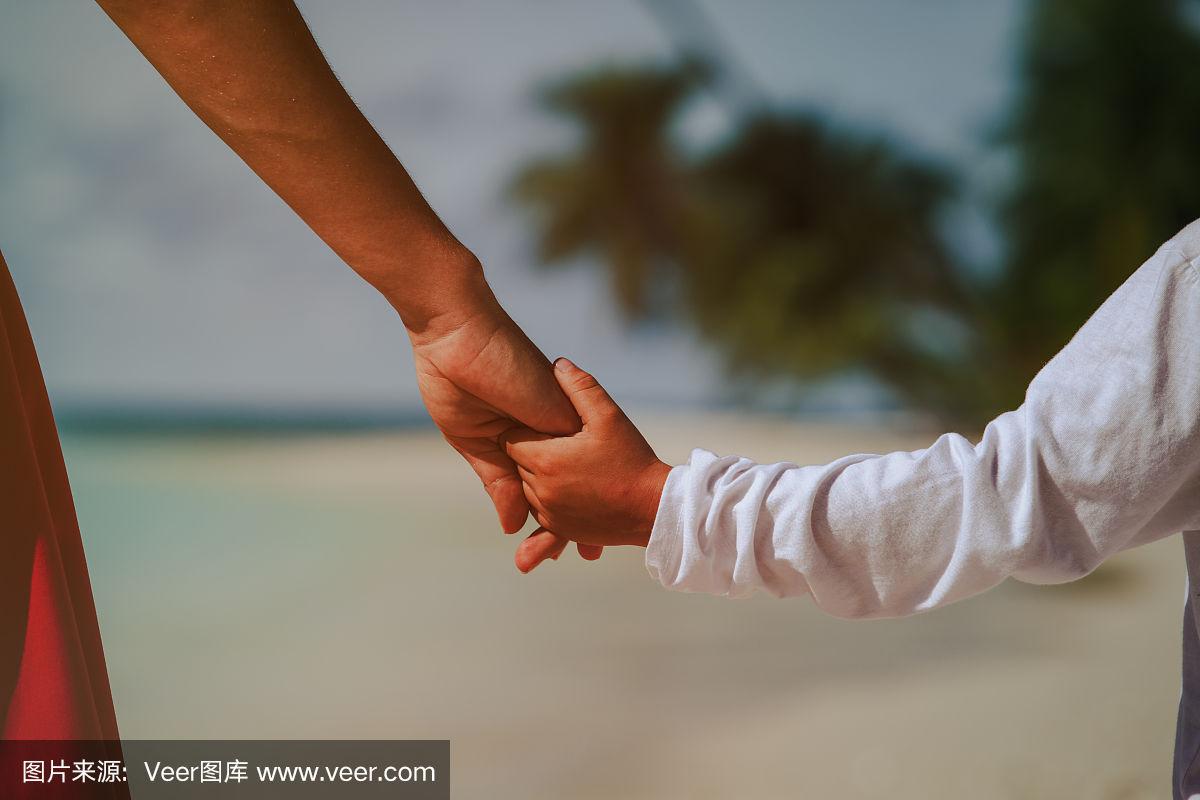 母亲和儿子手牵着手在海滩上