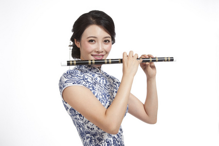 棚拍身穿旗袍的年轻女人吹笛子照片