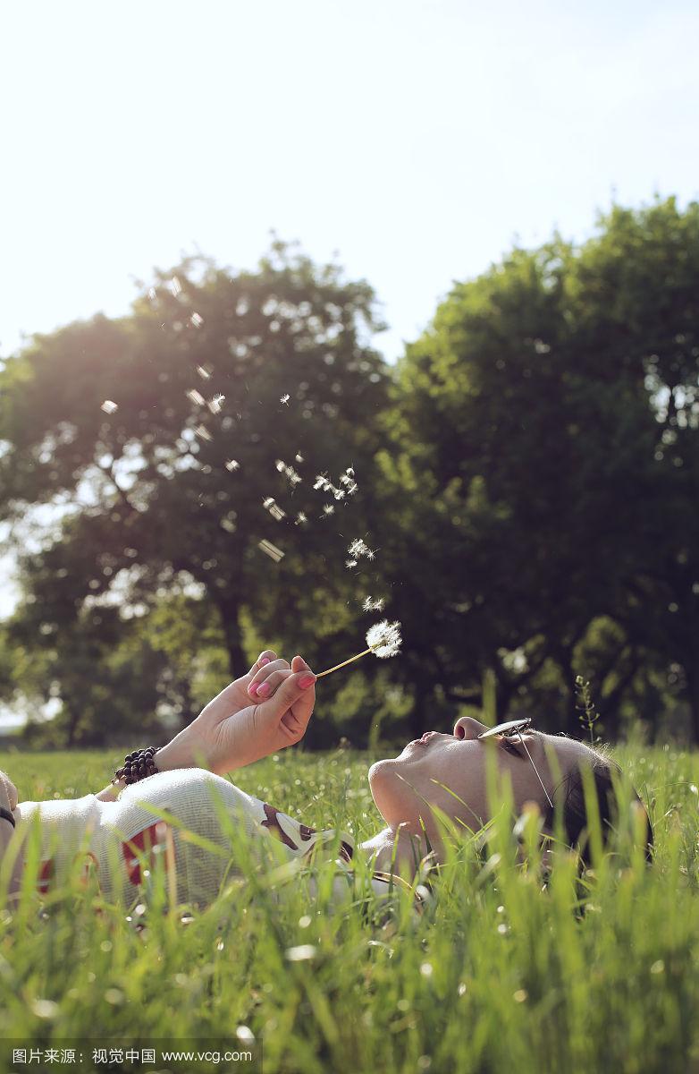 美丽的女孩吹蒲公英